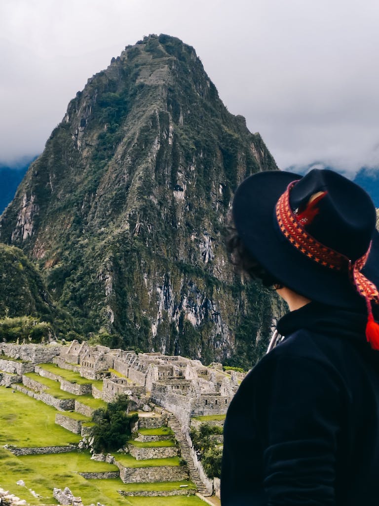 A woman in a hat looking at the ruins of machu picchu